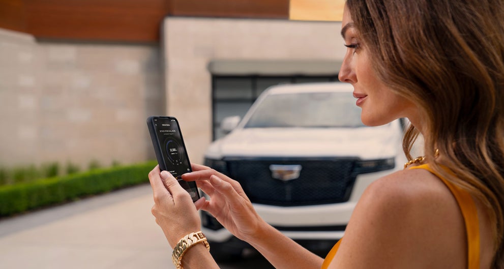 lady checking her mobile with a Cadillac vehicle background | Randy Marion Cadillac in Mooresville NC
